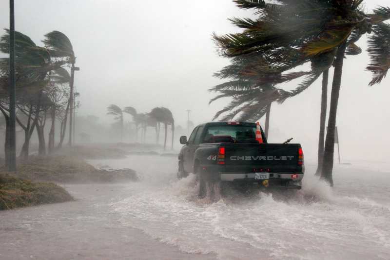 truck driving through flooded street with hurricane-force winds