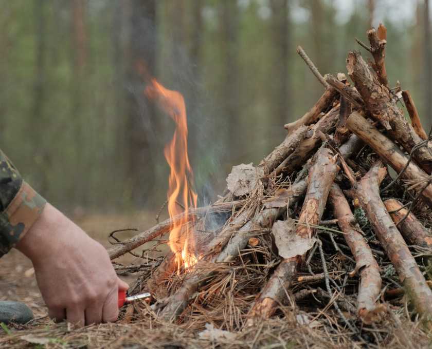 man starting a camp fire using natural tinder and kindling.